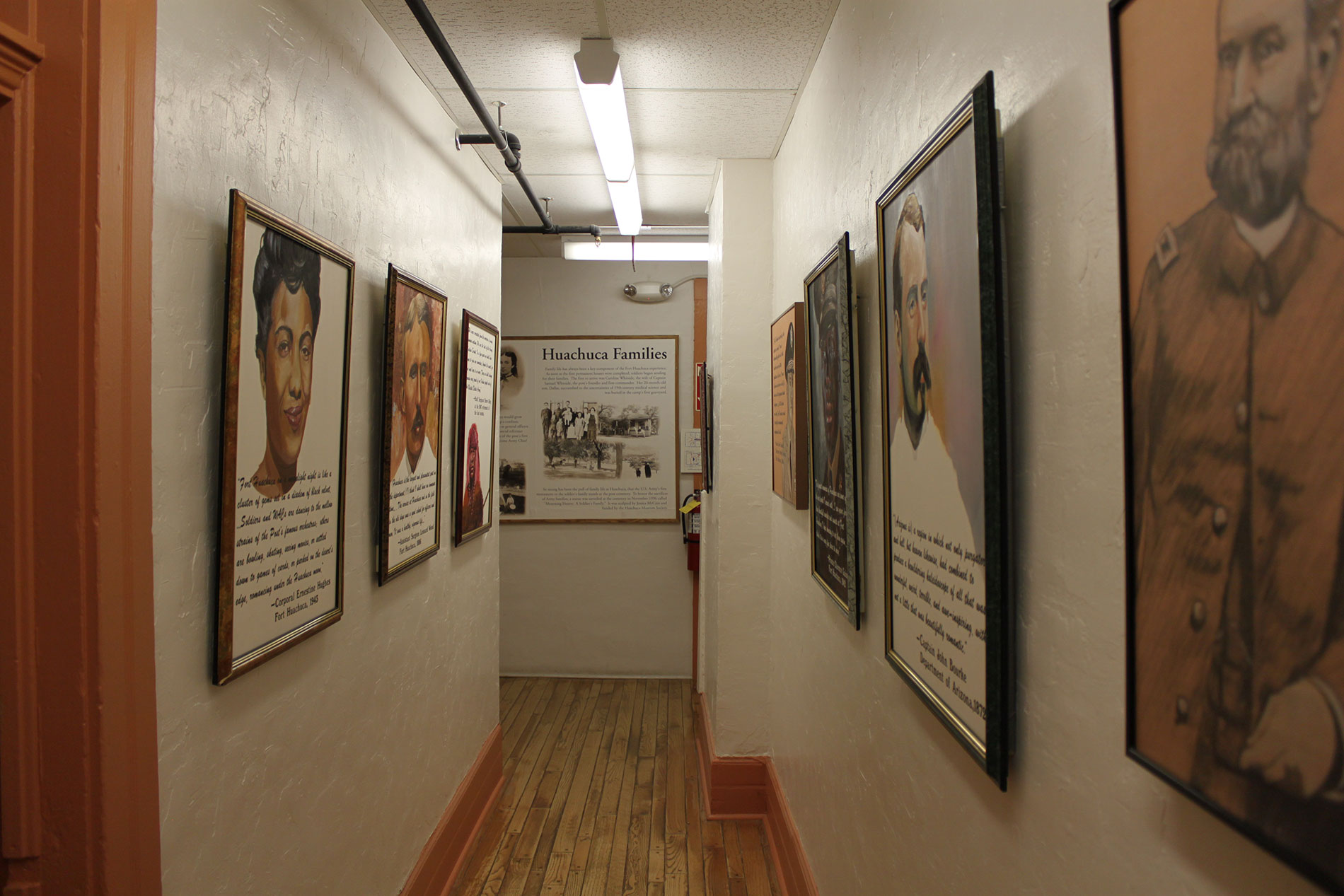 Several framed pictures hanging on walls in a narrow walkway inside a museum.